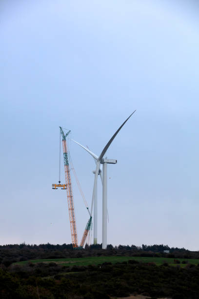 Wind turbine being repaired, assisted by crane and elevator