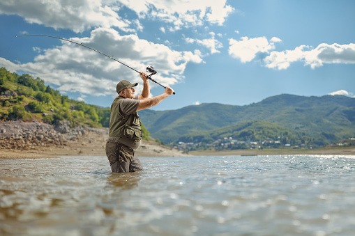 Fisherman throwing a fishing rod in a lake, Mavrovo lake, Macedonia