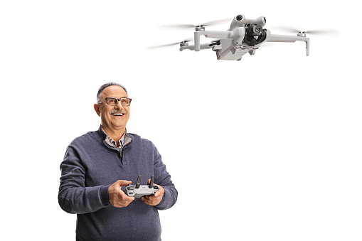 Happy mature man flying a drone isolated on white background