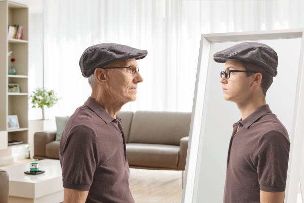 istock Old man looking at a mirror and remembering when he was young 2079615632