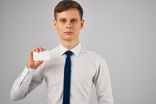 a man in a shirt with a tie holding a business card advertising Copy Space. High quality photo