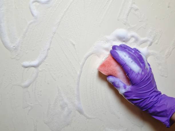 istock Hand wipes the wall with cleaning agent 2079625900