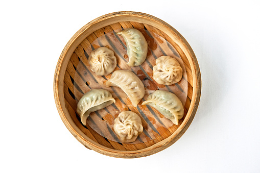 Oriental traditional chinese dumplings served in bamboo wood steamer on white background