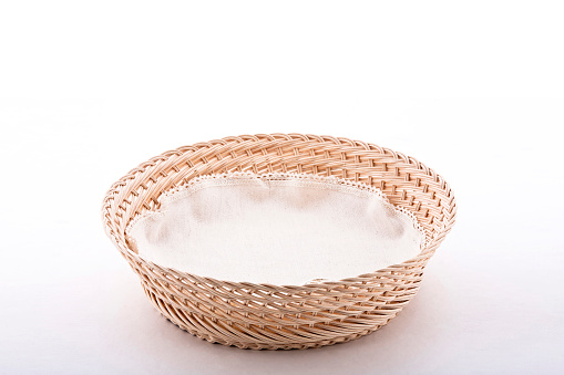 Empty wicker basket with cloth napkin, isolated on white background with space for text