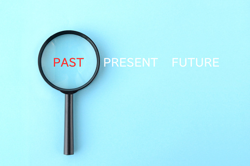 Magnifying glass with PAST, PREAENT and FUTURE word