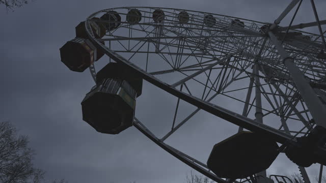 Black ferris wheel turning in entertainment park on dark sky background