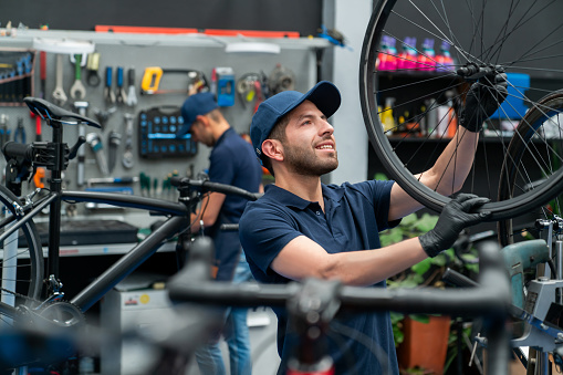 Team of Latin American mechanics working at a repair shop fixing the tire on a bicycle