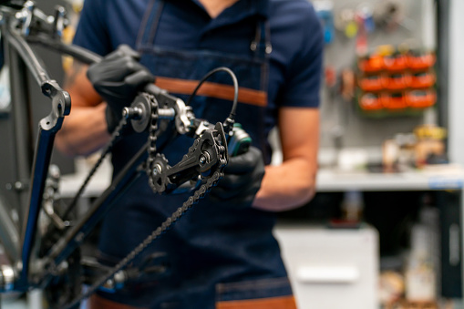 Close-up on a mechanic fixing a bicycle at a repair shop - vehicle breakdown concepts