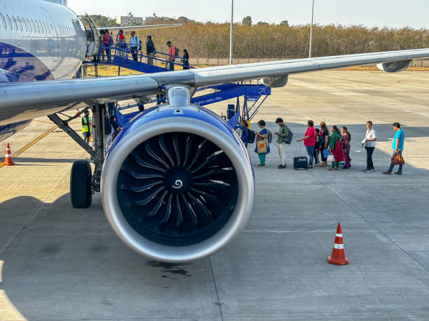 A jet engine is on the ground with people walking around it