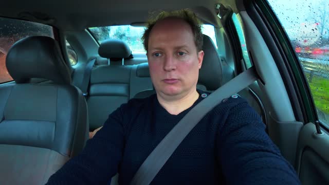 White caucasian adult man driving in car in traffic jam during morning
