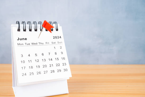 June 2024 calendar and red push pin on table.