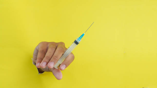 istock Hand holding disposable plastic syringe on yellow background 2079748946