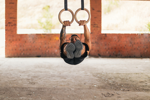 male athlete training with gymnastic rings. front lever