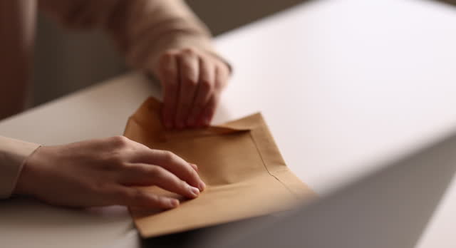 Girl hands opening an envelope on a desk at home