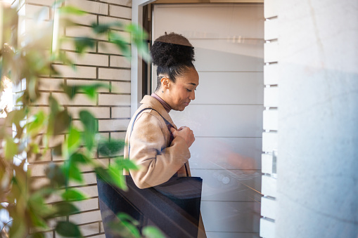 Mixed race woman in casual attire arriving to patients home, reflecting a caring and professional mood.