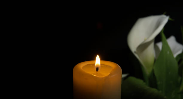 istock Burning wax candle and white calla lily flowers in darkness 2079907435