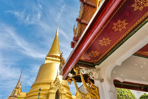 Phra Si Rattana Chedi, a gold bell-shaped stupa, framed by the decorative underside of a pavilion at the Wat Phra Kaew (Temple of the Emerald Buddha) - Grand Palace, Phra Nakhon, Bangkok, Thailand
