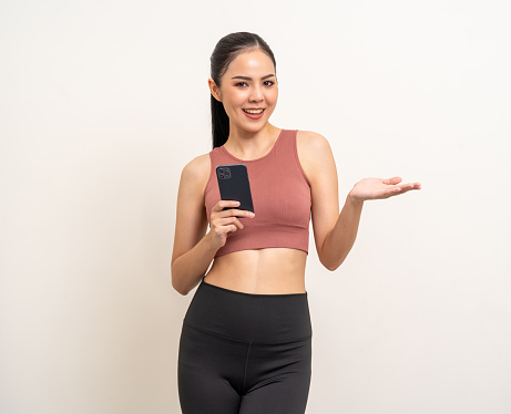 Young beautiful asian woman with sportswear using smartphone and open hand palm up to copy space for text on isolated. Attractive Portrait latin sporty woman pose holding cell phone on blank space