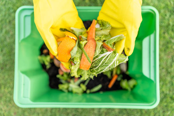 istock Ecology compost supply Kitchen waste recycling composter environmentally friendly. The young man throws leftover fruit peel egg shell and vegetables reduce waste 2079950635