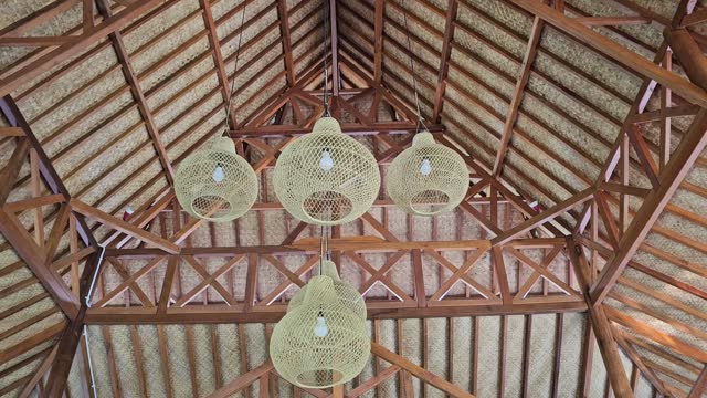 Decorative bamboo lamps hanging from the roof of a traditional Indonesian wood house