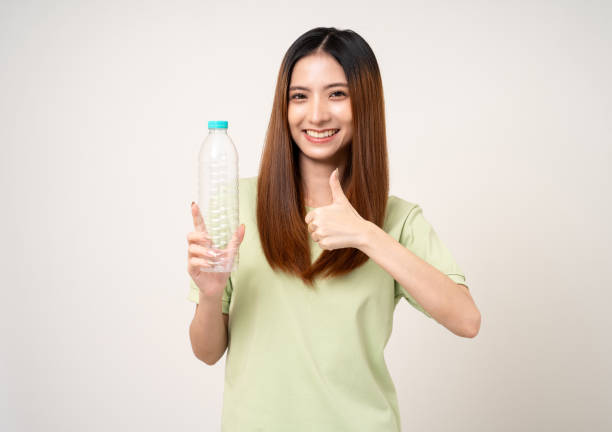 istock Young asian beautiful woman holding plastic of bottle assume Garbage sorting before throwing them into the bin. Activist environmental woman in green shirt with recycle and sustainability concept. 2079990081