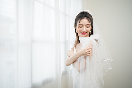 Beautiful asian bride with fashion wedding hairstyle and makeup. Portrait of young gorgeous bride wedding studio shot in white room.