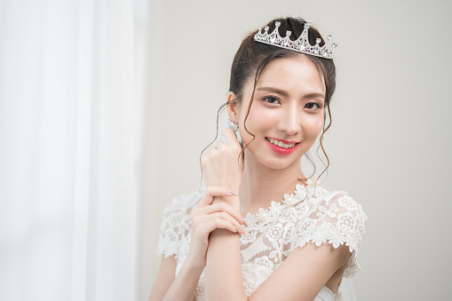Beautiful asian bride with fashion wedding hairstyle and makeup. Portrait of young gorgeous bride wedding studio shot in white room.