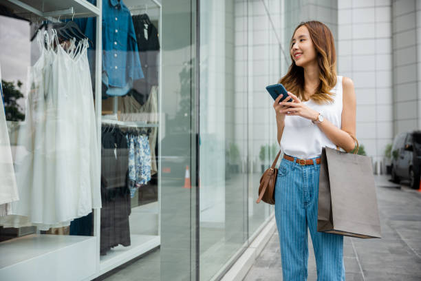 istock person looking at her phone while standing against a city wall 2080038520