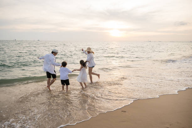 istock Captivating sunset on beach where parents playfully interact with their kid during holiday. essence of summer vacation is captured joyful family including happy mother father and children run in ocean 2080039075