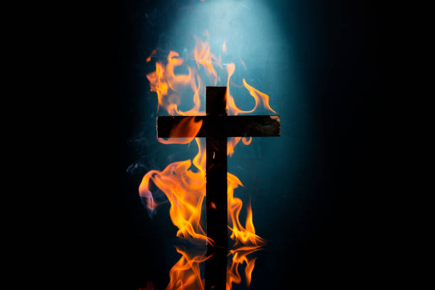 istock Wooden cross covered with fiery flames isolated on black background with copy space. 2080098416