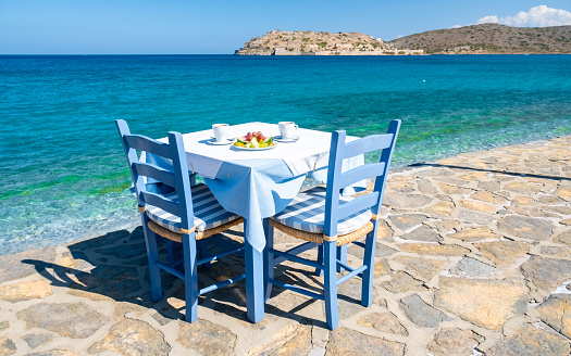 Crete Greece Plaka Lassithi, a traditional blue table and chairs on the beach in Crete Greece. Paralia Plakas, Plaka village Crete.