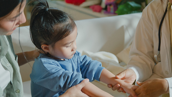 Closeup of A female doctor is checking the skin of a girl who gets sick and has a high fever, at home. Illness Girl stays with her mom with a medical condition and family wellness concept.