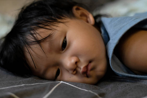 Little boy lied down on bed and fell asleep or napping or sad.
