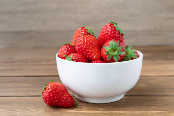 istock Strawberries in White Bowl on Wooden Table 2080145382