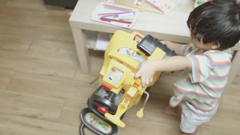 Happy Asian boy plays with a bulldozer in the living room at home.