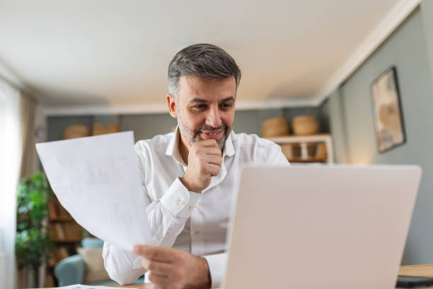 istock Handsome man working in office at desk with laptop and documents. an envelope with a letter, bills, and reports, good news. 2080176034