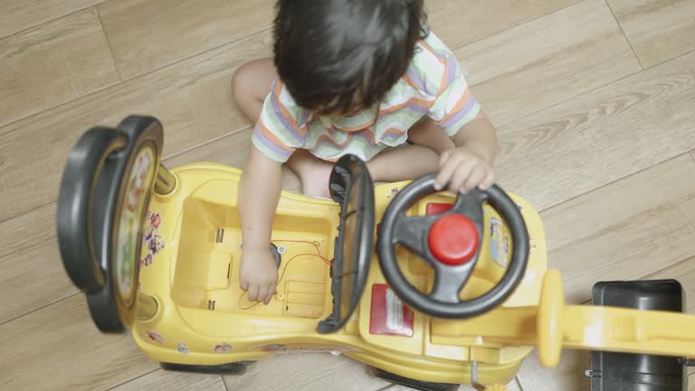 Happy Asian boy playing with toy backhoe in the living room at home. Drive to repairs with imagination.