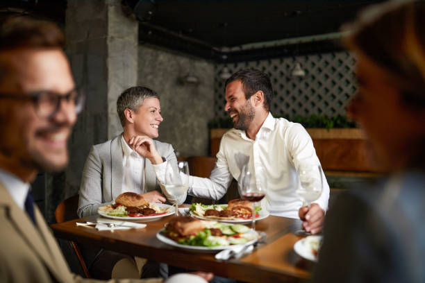 Cheerful entrepreneurs talking on a lunch with their colleagues in a restaurant.