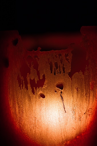Handmade red color wax candle lit and fire indoor