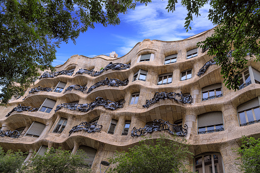 Casa Milà is characterized by its self-supporting stone facade. The curved facade is a unique example of organic architecture: the front of the house looks like a solid rock, which is only broken up by wavy lines and ornaments hammered out of iron.