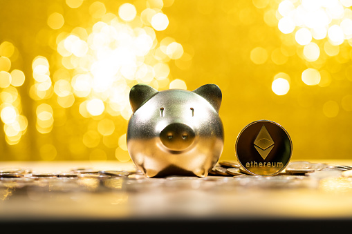 Fujian, China - December 23, 2021: Ethereum cryptocurrency and piggy bank on shiny background.