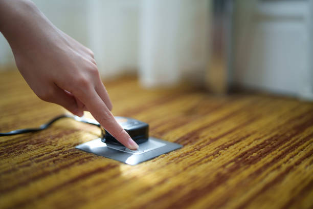 Close up of a hand switching on a plug socket from an electrical outlet on the floor.