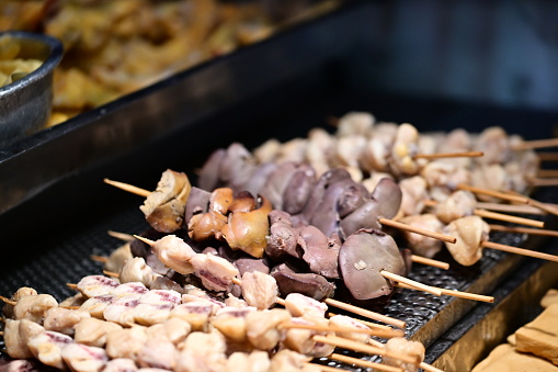 A close-up of the rows of chicken offal on the grill stand at Ningxia Night Market in Taiwan. Skewered chicken butts are also displayed on the side.
