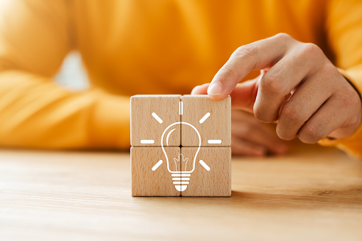 Innovation through ideas and inspiration ideas, Wooden cube block with icon light bulb, idea of creativity and inspiration concept of sustainable business development.
