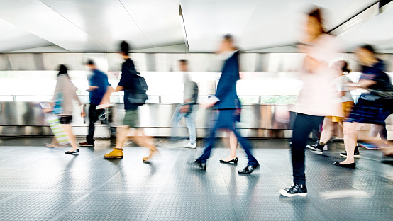 Blurred commuters walking on footbridge