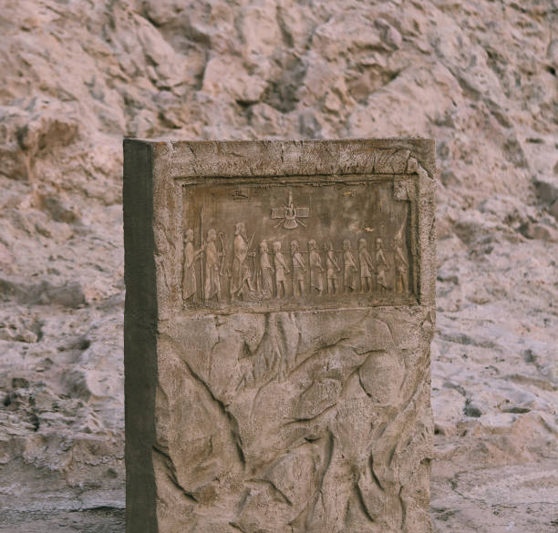 Stone block with carvings in front of cliff