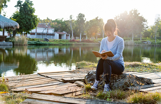 Woman reading a book by the lake.
