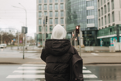 Tourist teenage girl traveling alone through the city streets in the autumn-winter season. Modern solo travel, lone traveler, Winter vacation railroad adventure concept