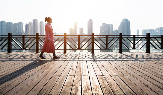 Woman walking on the boardwalk by the sea.