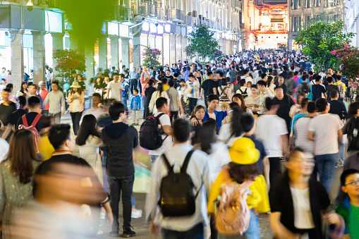 Crowd of people walking on city street at night.